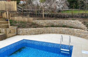 Polished sandstone pool area with Purbec stone & sleeper retained beds.