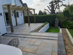 Lovely patio laid in sawn and honed sandstone, limestone banding with pergola